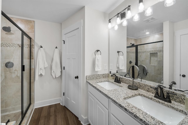 bathroom with a sink, a stall shower, and wood finished floors