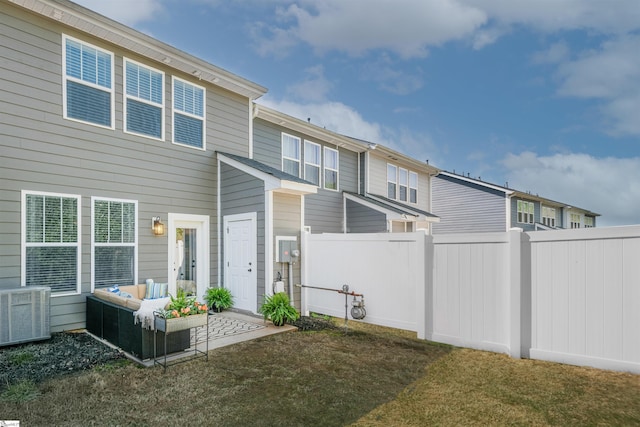 rear view of property featuring fence, cooling unit, a lawn, and an outdoor hangout area