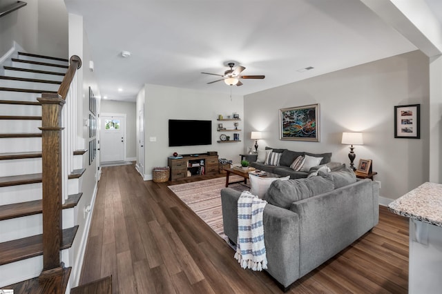 living area featuring dark wood finished floors, baseboards, a ceiling fan, and stairway