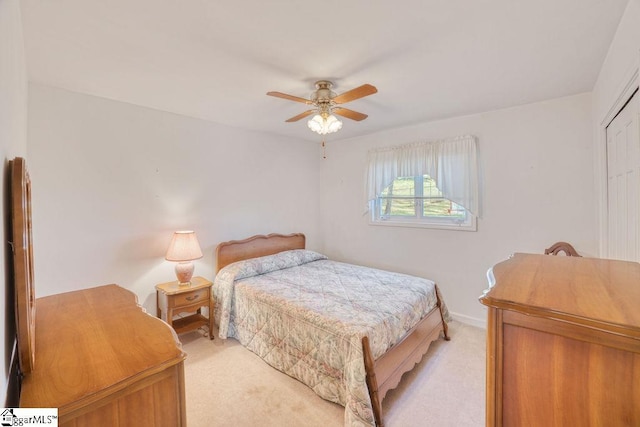bedroom featuring light carpet, baseboards, a closet, and a ceiling fan