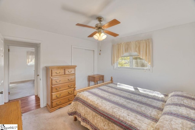 bedroom with light carpet, a closet, baseboards, and a ceiling fan