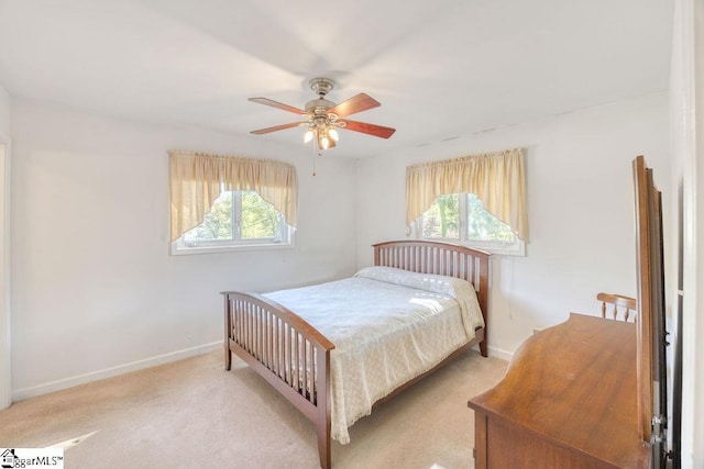 bedroom featuring baseboards, multiple windows, light carpet, and a ceiling fan