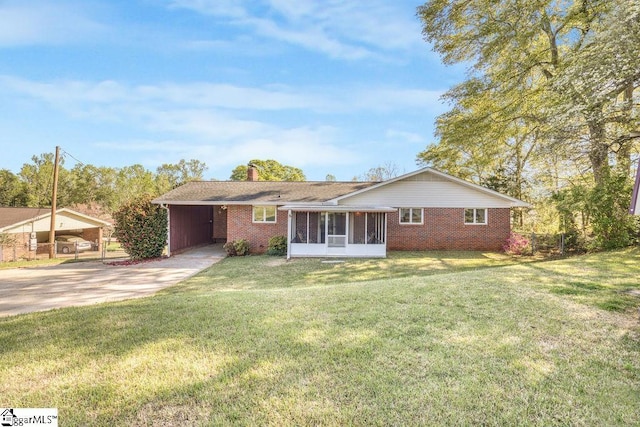 view of front of property featuring a front yard, brick siding, a sunroom, and driveway