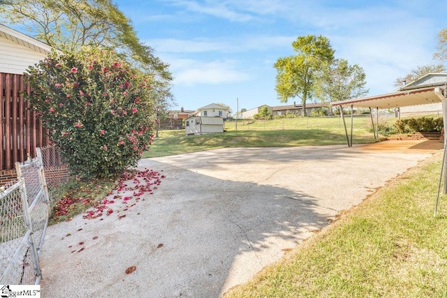view of patio featuring a carport, driveway, and fence