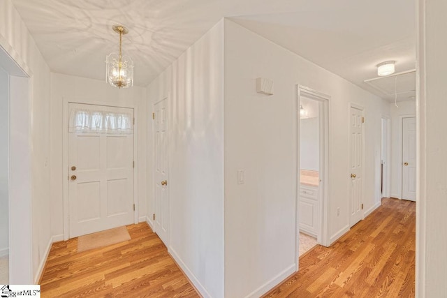 foyer entrance featuring a chandelier, light wood finished floors, and baseboards