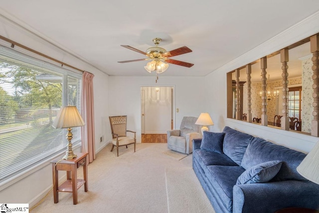 living area with baseboards, light colored carpet, and ceiling fan with notable chandelier