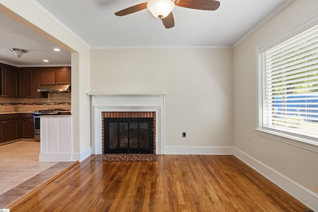 105 Pinewood Ave, Clinton, SC 29325 - unfurnished living room featuring crown molding, ceiling fan, a brick fireplace, light wood finished floors, and baseboards