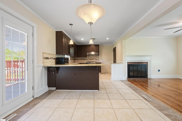 105 Pinewood Ave, Clinton, SC 29325 - kitchen featuring light tile patterned floors, open floor plan, dark brown cabinetry, under cabinet range hood, and crown molding