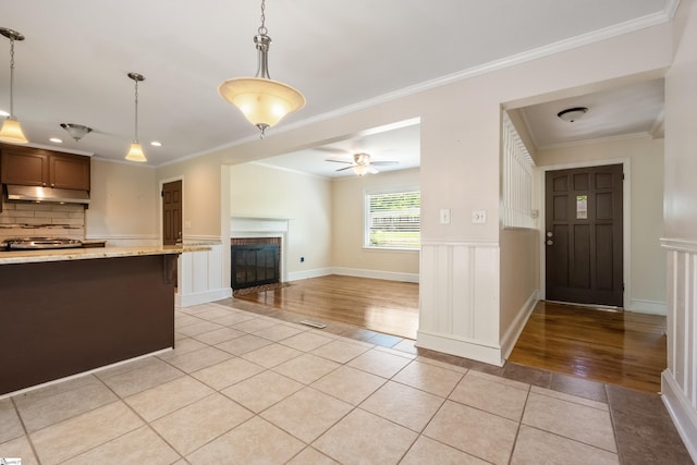 105 Pinewood Ave, Clinton, SC 29325 - kitchen with a glass covered fireplace, light tile patterned floors, crown molding, backsplash, and under cabinet range hood