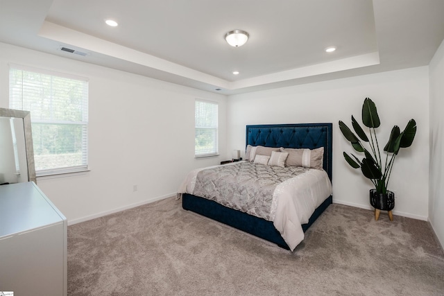 bedroom featuring carpet flooring, visible vents, a tray ceiling, and baseboards