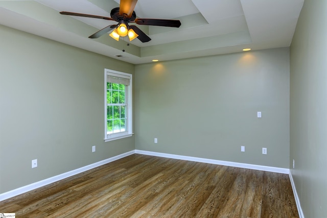 spare room with baseboards, wood finished floors, and a raised ceiling