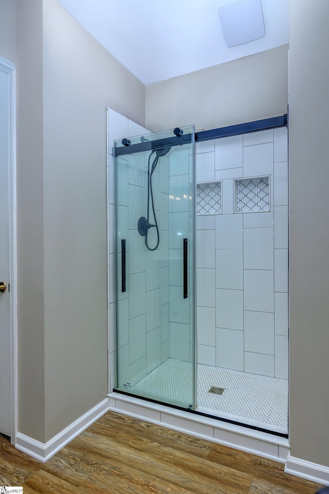 full bathroom featuring a stall shower, wood finished floors, and baseboards