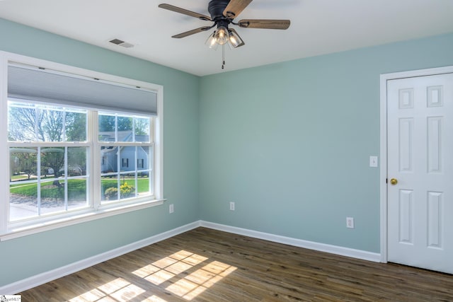 empty room with visible vents, baseboards, a ceiling fan, and dark wood finished floors