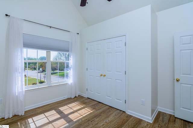 unfurnished bedroom featuring baseboards, wood finished floors, a closet, and vaulted ceiling