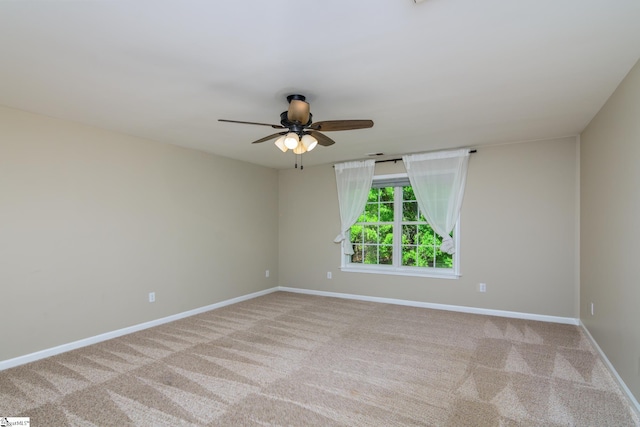carpeted spare room with baseboards and a ceiling fan
