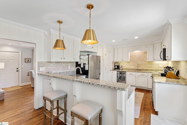 kitchen featuring appliances with stainless steel finishes, ornamental molding, beverage cooler, and wood finished floors