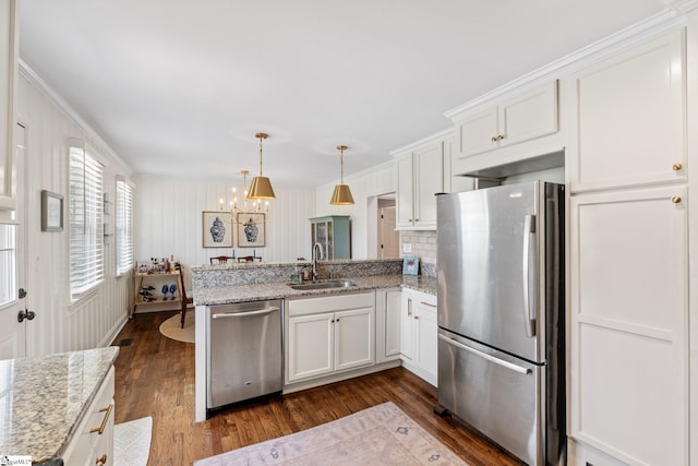 kitchen featuring a peninsula, dark wood-style floors, white cabinetry, stainless steel appliances, and a sink