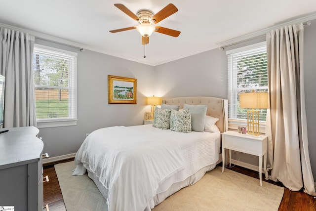 bedroom featuring baseboards, multiple windows, ornamental molding, and wood finished floors