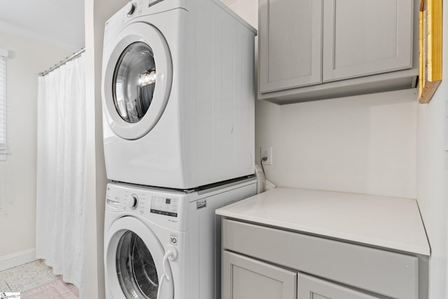 clothes washing area featuring stacked washer / dryer and cabinet space