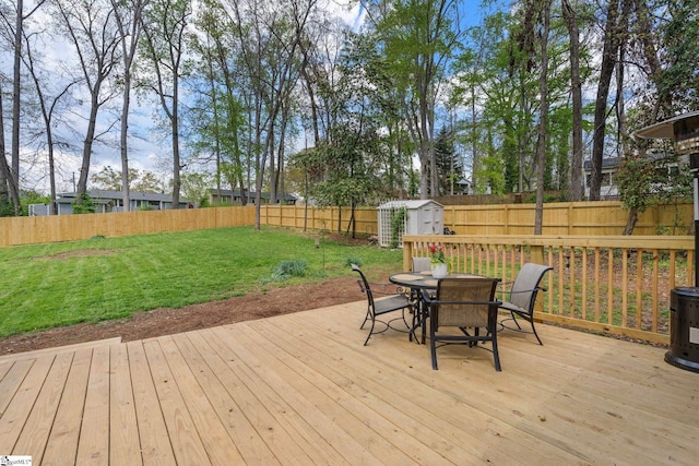 wooden deck featuring a shed, a lawn, a fenced backyard, an outdoor structure, and outdoor dining area