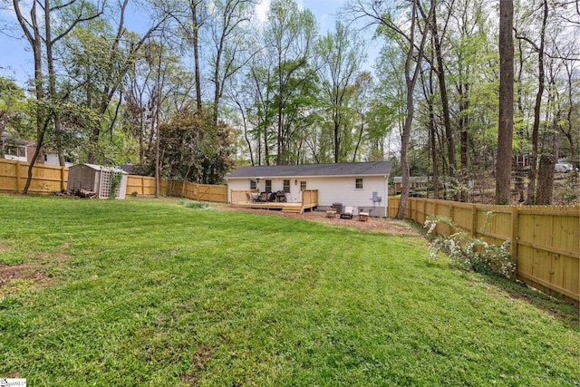 view of yard with a wooden deck, a fenced backyard, and an outdoor structure