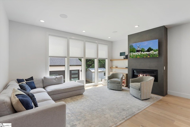 living room with baseboards, recessed lighting, a glass covered fireplace, and wood finished floors