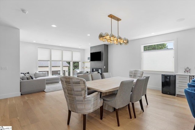 dining room with a wealth of natural light, recessed lighting, a glass covered fireplace, and light wood-style floors
