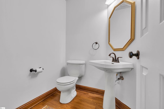 half bathroom featuring toilet, baseboards, and wood finished floors
