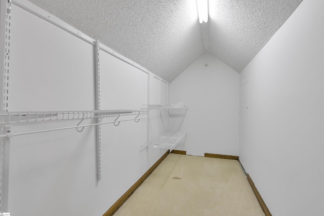 spacious closet featuring light colored carpet and vaulted ceiling