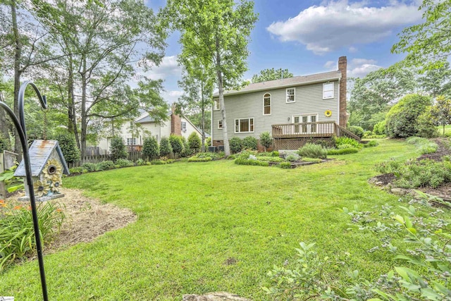 back of property featuring a yard, a wooden deck, fence, and a chimney