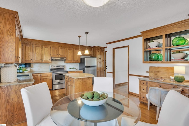 kitchen with light wood-style flooring, a center island, appliances with stainless steel finishes, under cabinet range hood, and light countertops