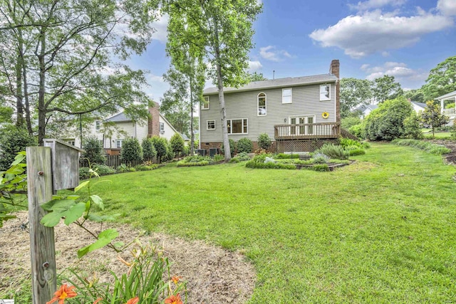 rear view of property with a yard, a wooden deck, fence, and a chimney