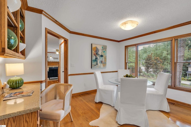 dining area with light wood-style flooring, crown molding, and a textured ceiling