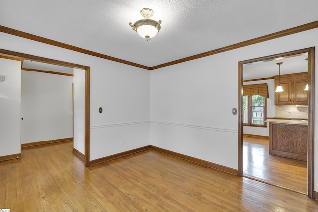 unfurnished room featuring ornamental molding, baseboards, light wood-type flooring, and a textured ceiling