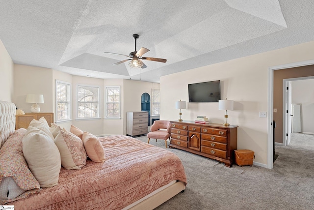 bedroom featuring a tray ceiling, baseboards, carpet floors, and a textured ceiling