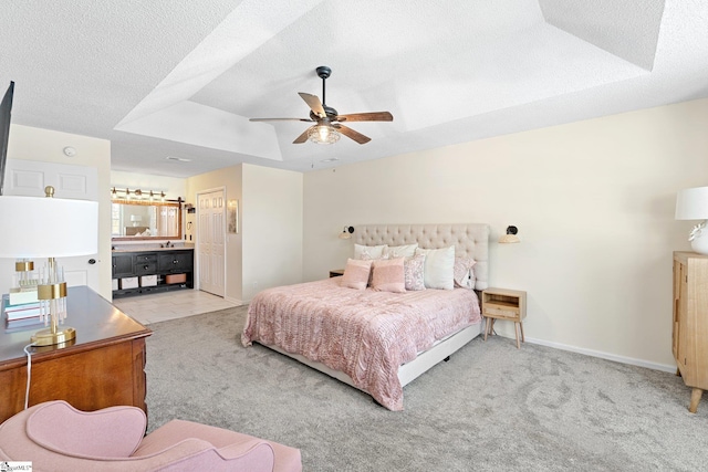 bedroom with baseboards, carpet, a tray ceiling, and a textured ceiling