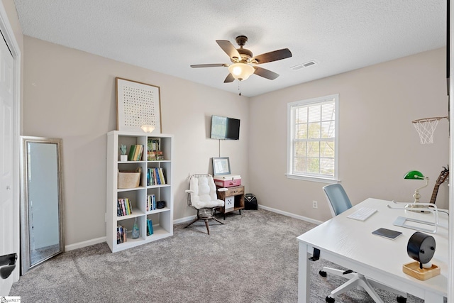 carpeted home office with baseboards, visible vents, a textured ceiling, and a ceiling fan