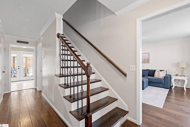 staircase with crown molding, french doors, and hardwood / wood-style floors