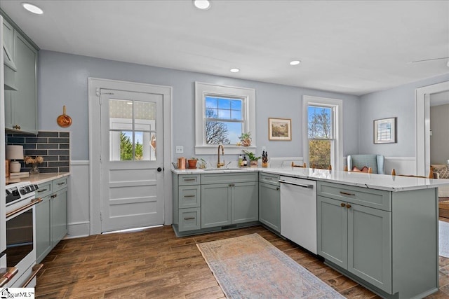 kitchen with a peninsula, gray cabinetry, dishwasher, and range
