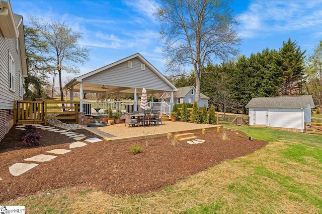 view of yard with an outdoor structure, a patio area, ceiling fan, fence, and a storage unit