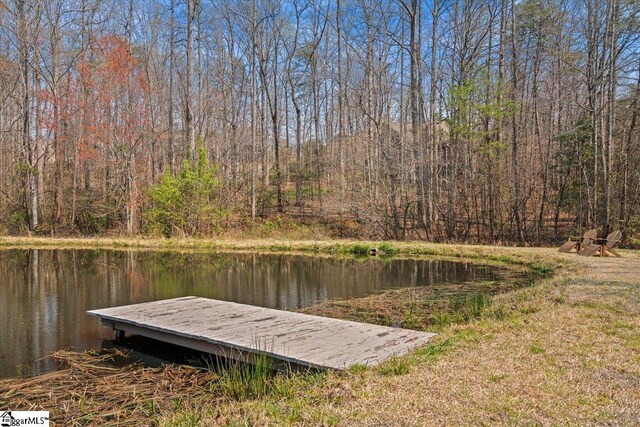 view of dock with a water view and a wooded view