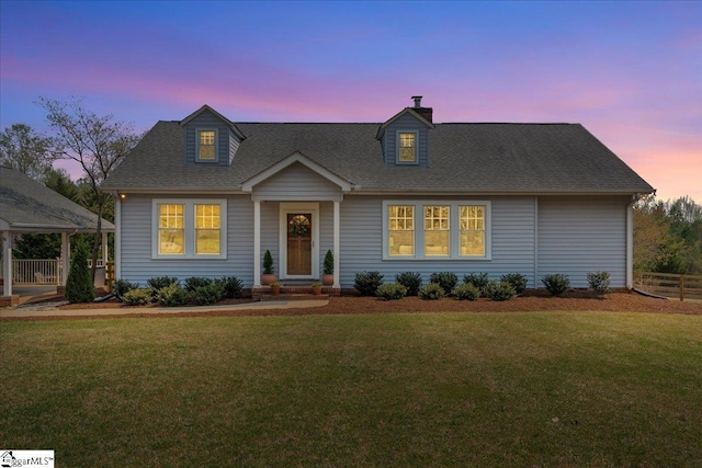 cape cod house featuring roof with shingles, a chimney, fence, and a front lawn