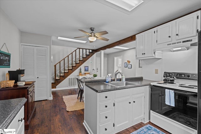 kitchen featuring a peninsula, dark countertops, under cabinet range hood, range with electric stovetop, and a sink