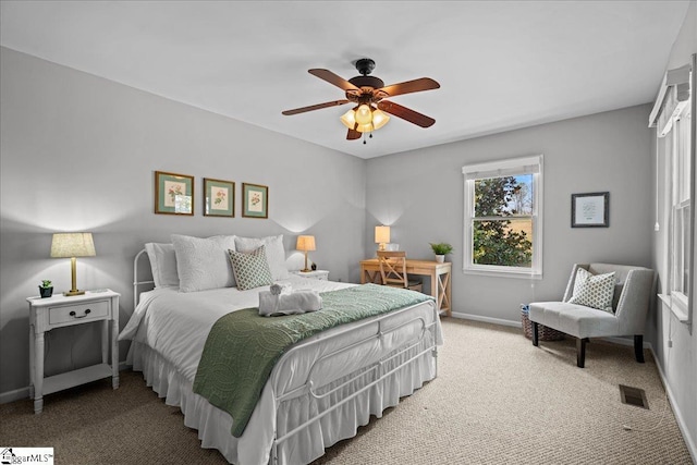 carpeted bedroom with visible vents, baseboards, and a ceiling fan