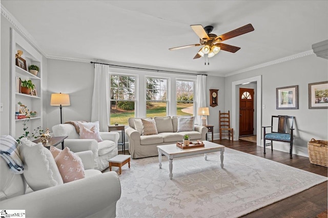 living area with wood finished floors, ornamental molding, a ceiling fan, and built in features