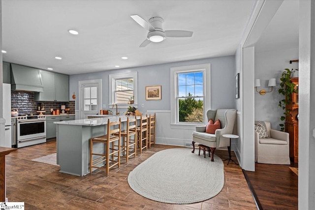 kitchen featuring premium range hood, light countertops, a breakfast bar area, ceiling fan, and white range with electric stovetop