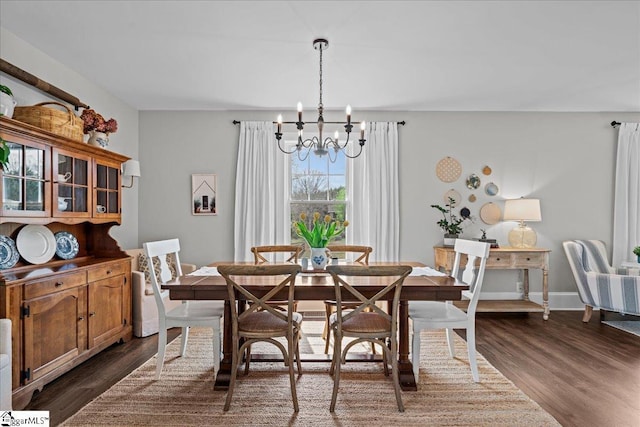 dining room with dark wood-type flooring, a notable chandelier, and baseboards