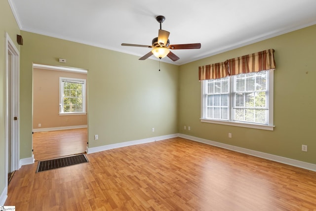 empty room with light wood-style floors, baseboards, ornamental molding, and visible vents
