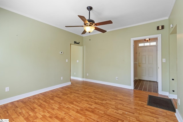 interior space with baseboards, light wood-type flooring, ornamental molding, and ceiling fan