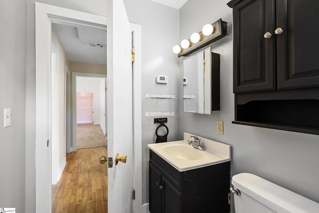 half bath featuring toilet, vanity, and wood finished floors